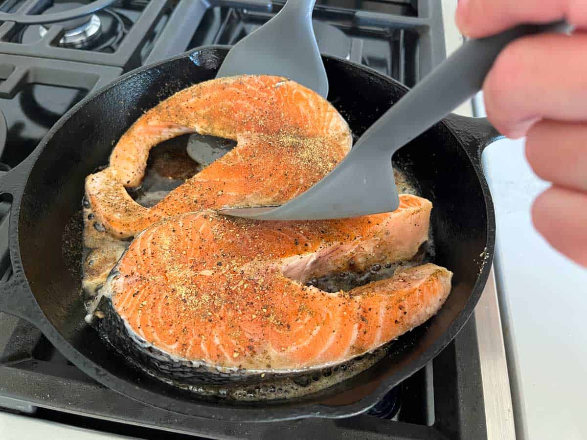 Flipping the steaks with two wide spatulas.