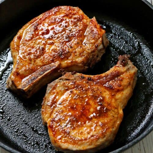 Baked pork chops are served in a cast-iron skillet.