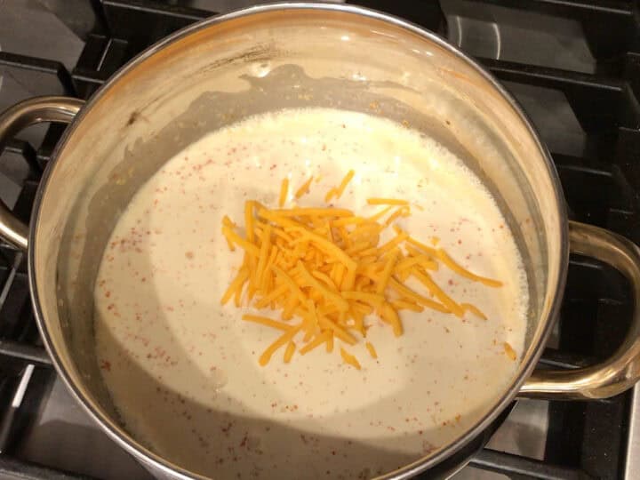 Adding cheese to the heavy cream mixture.