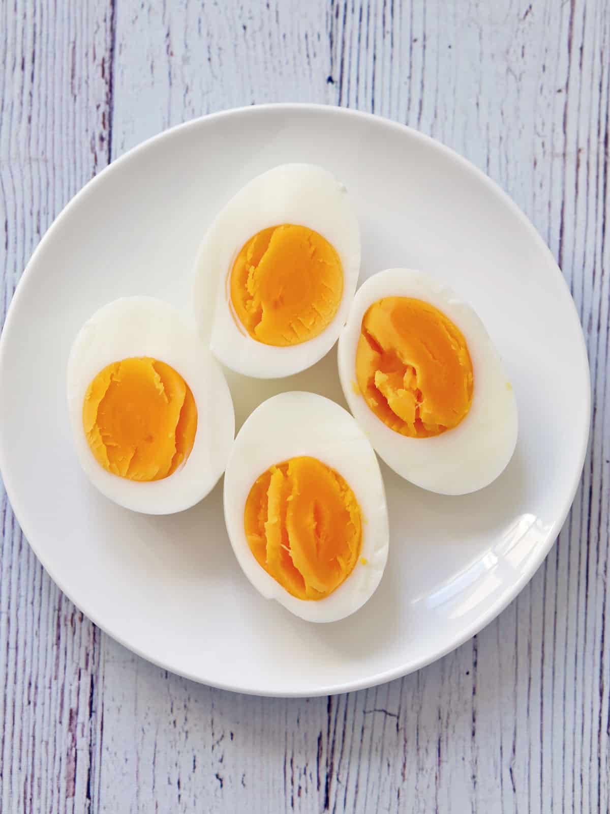 Hard-boiled eggs are served on a white plate.