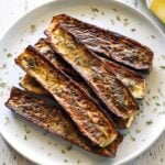 Roasted zucchini is served on a white plate.