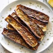 Roasted zucchini is served on a white plate.