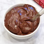 Avocado chocolate mousse is served in a white bowl with a spoon.