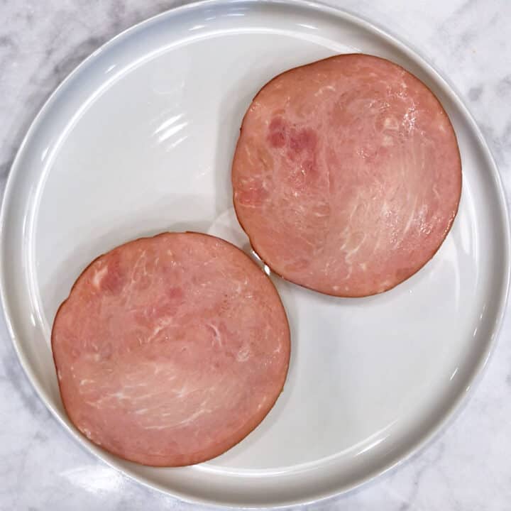 Two pieces of Canadian bacon on a plate.