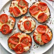Eggplant pizza is served on a white plate.