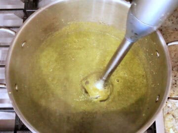 Blending the soup with an immersion blender.