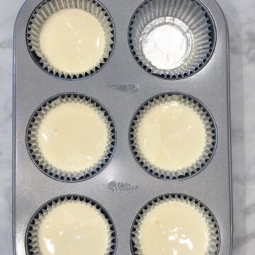 The batter was divided between the muffin liners.