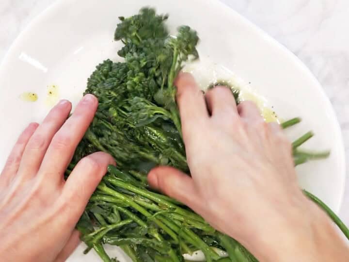 Coating the broccolini with the oil and spices.
