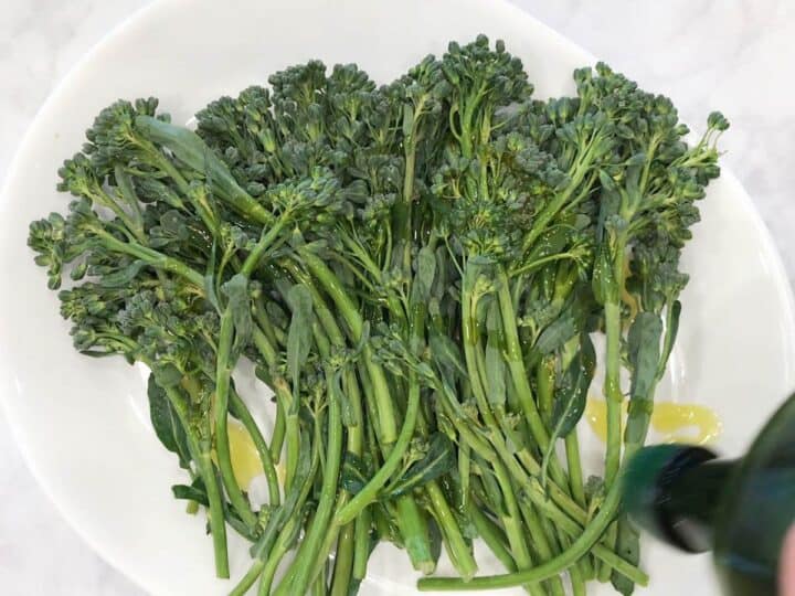 Drizzling the broccolini with olive oil.