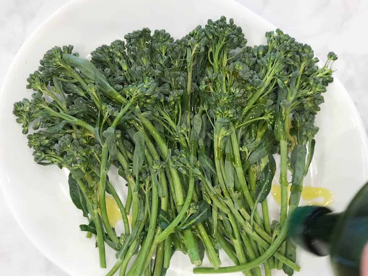 Drizzling the broccolini with olive oil.