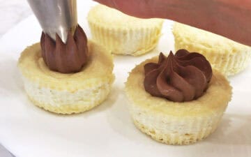Topping the cakes with chocolate whipped cream.