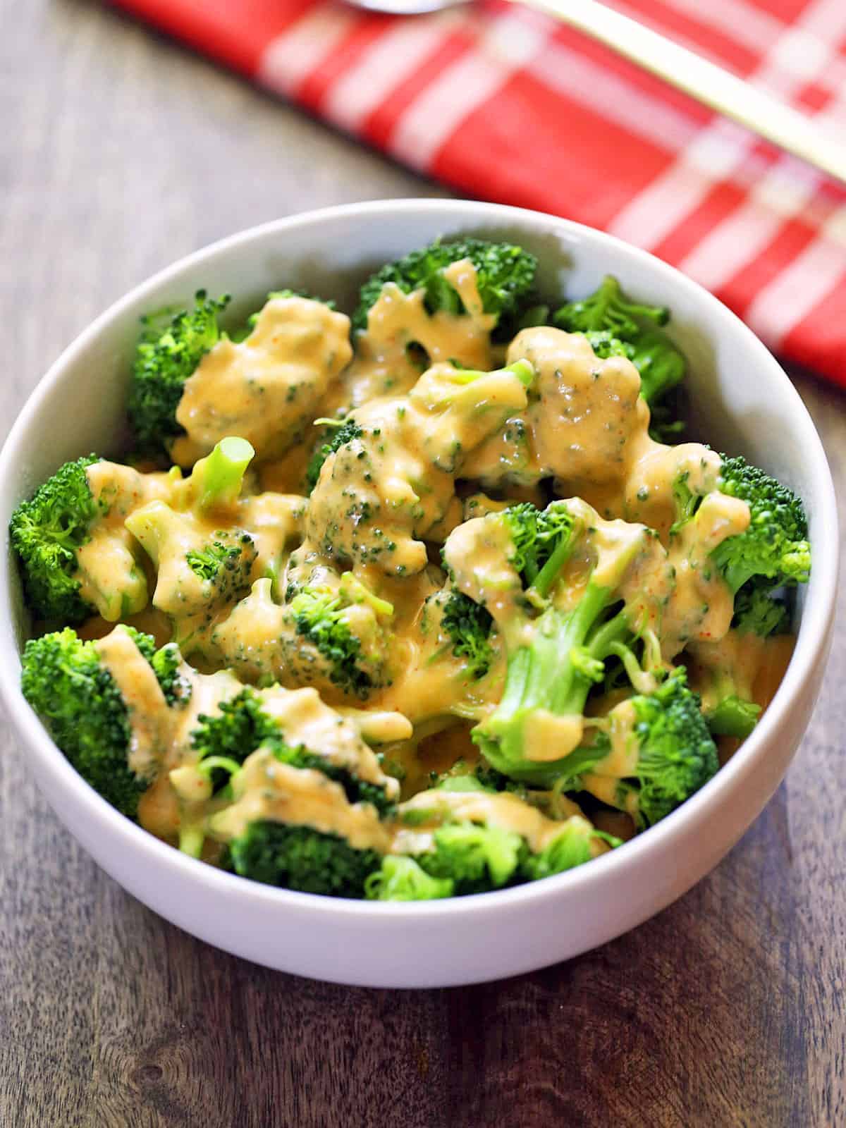 Broccoli and cheese is served in a white bowl.
