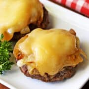 Broiled burgers are served on a white plate.