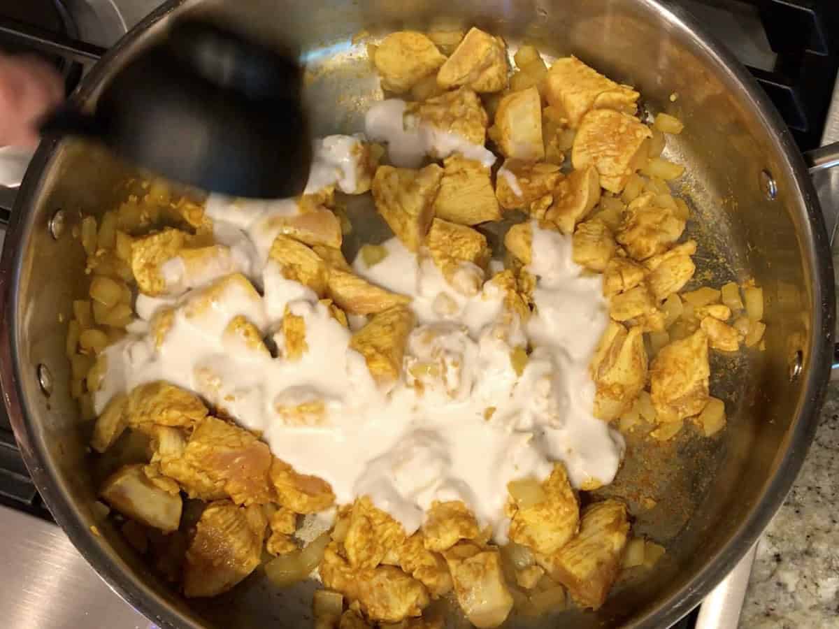Adding coconut milk to skillet.