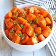 Honey glazed carrots are served in a white bowl.