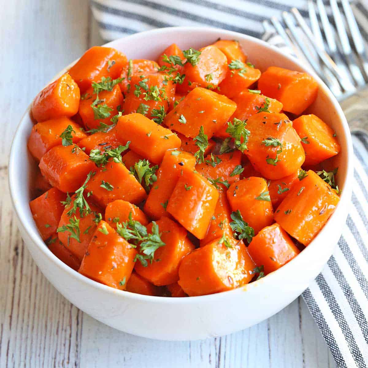 Honey glazed carrots are served in a white bowl.