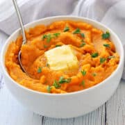 Mashed sweet potatoes are served in a white bowl.