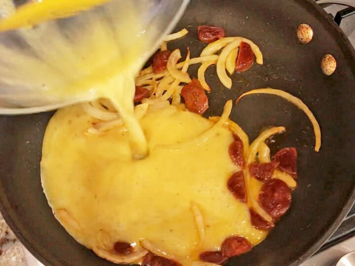 Pouring the eggs into the skillet.