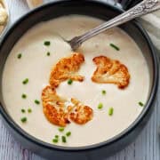 Cauliflower soup is served in a bowl with a spoon.