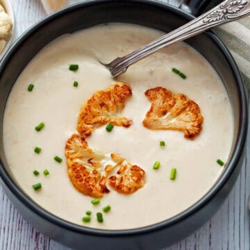 Cauliflower soup is served in a bowl with a spoon.