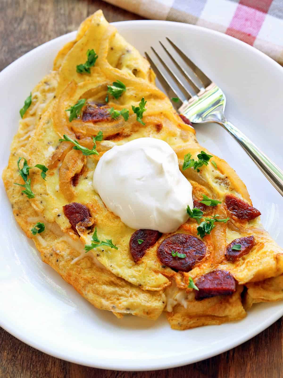 Chorizo omelette is served on a white plate with a fork.
