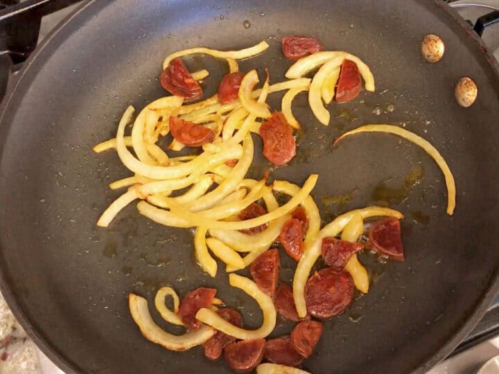 Cooking the onions and chorizo in a skillet.