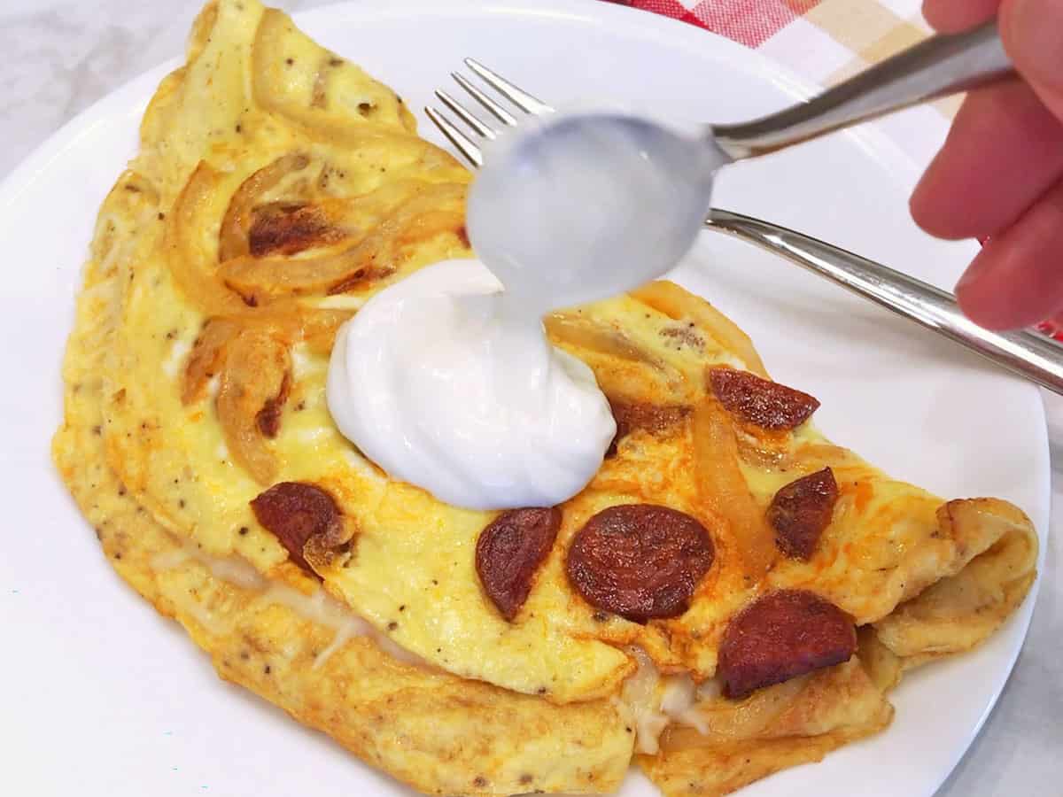 Topping the omelette with a dollop of sour cream before serving.