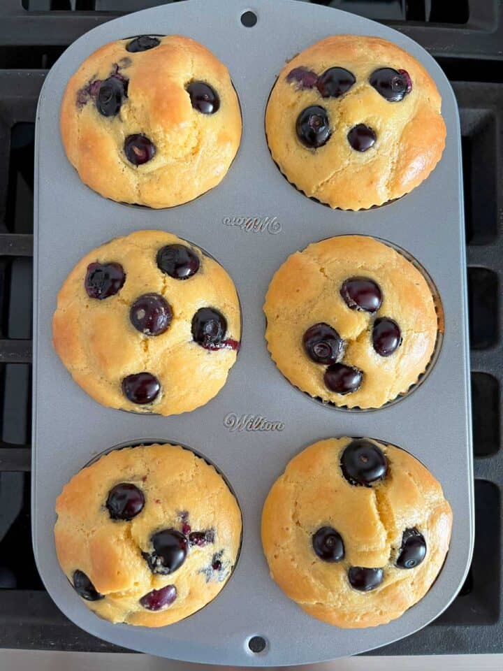 Six keto blueberry muffins in a baking pan.