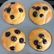 Four keto blueberry muffins in a muffin pan.